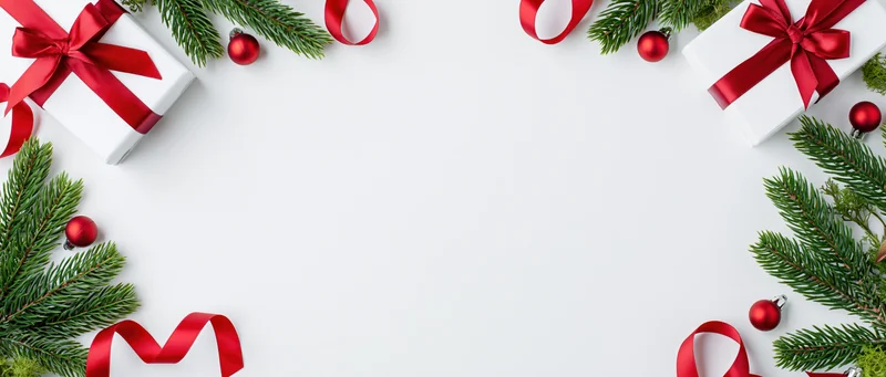 Christmas border arrangement with gifts, ribbons and pine sprigs on white surface