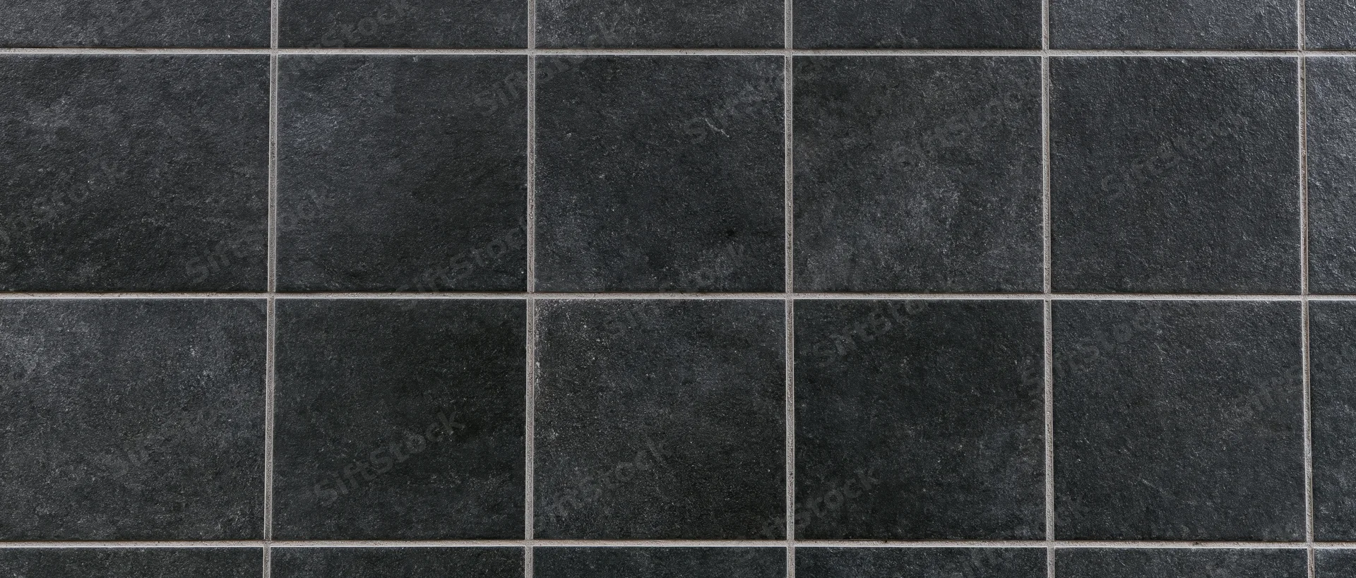 Close-up of large square black ceramic tiles arranged in a grid pattern on a flat surface