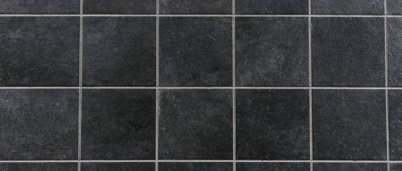Close-up of large square black ceramic tiles arranged in a grid pattern on a flat surface
