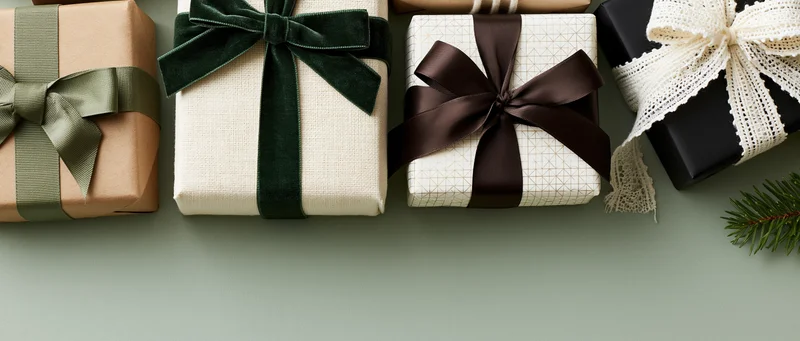 Assorted wrapped gift boxes arranged neatly on a flat surface with pine sprig and copyspace below