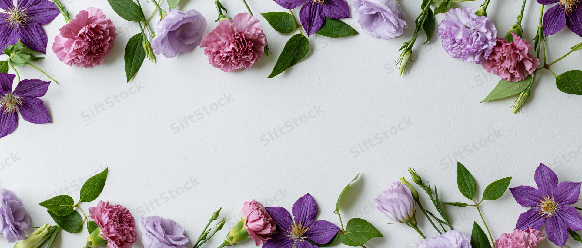 Loose purple and pink flowers arranged in a border along the edges of a white surface with copyspace in the center