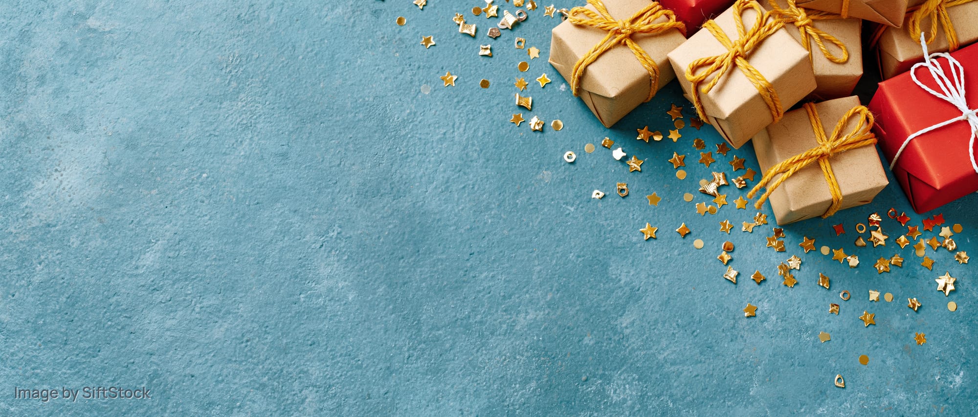 Small wrapped gift boxes with gold star confetti on blue surface