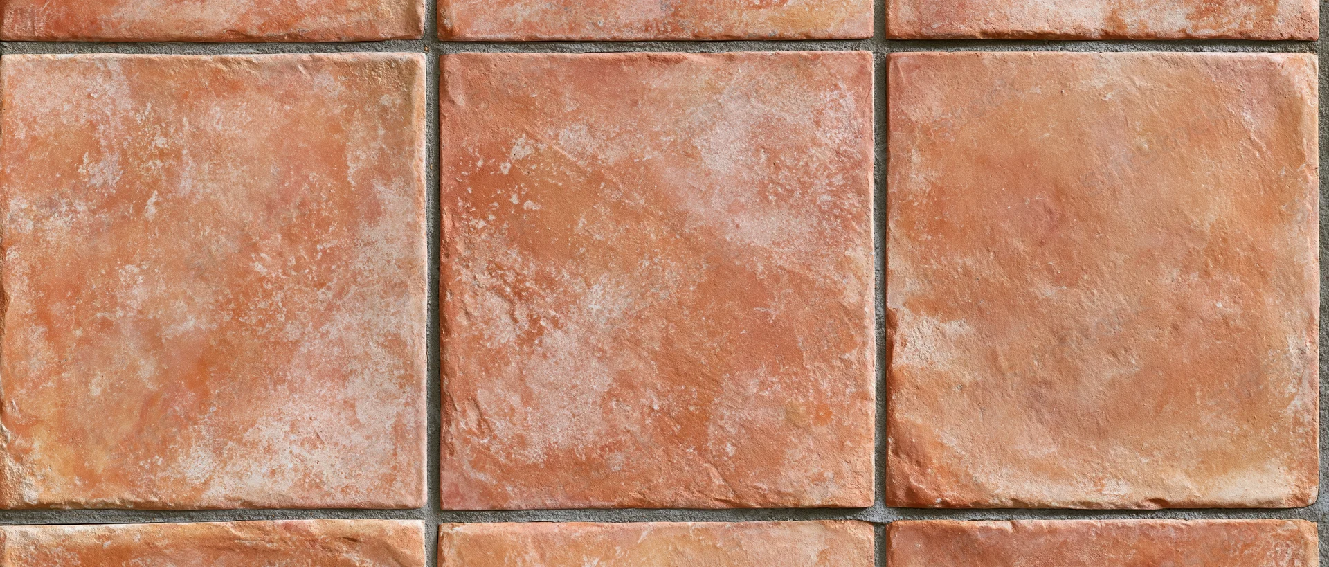 Aged terracotta tiles arranged in a grid pattern on a floor