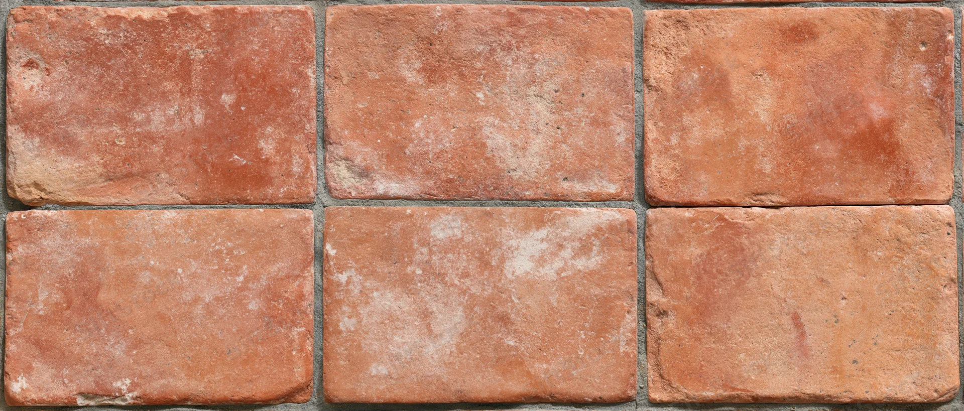 Aged terracotta floor tiles arranged in grid pattern with visible grout lines