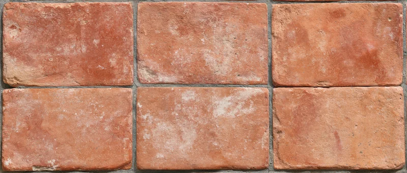 Aged terracotta floor tiles arranged in grid pattern with visible grout lines