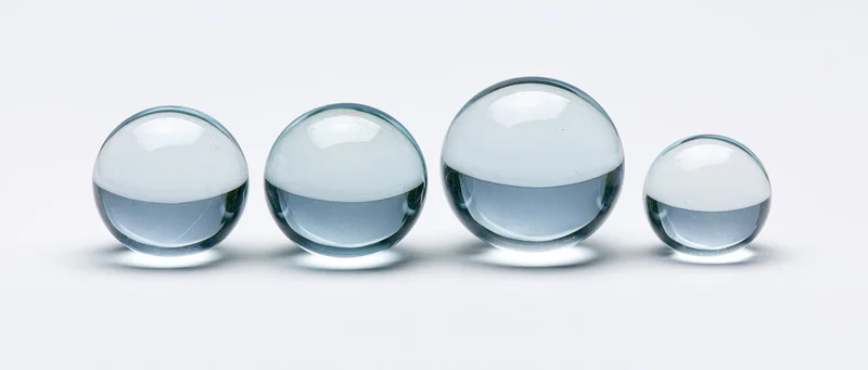 Four clear glass spheres arranged in a row on a white background