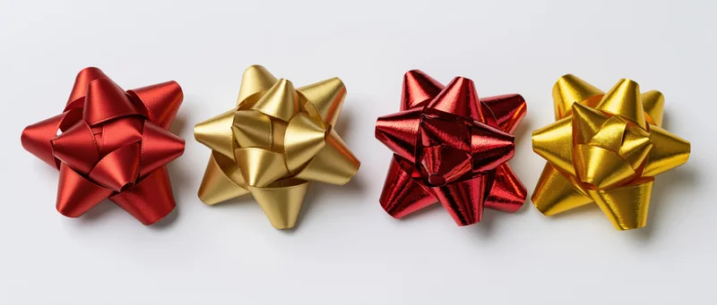 Four decorative gift bows in red and gold arranged in a row on a white background
