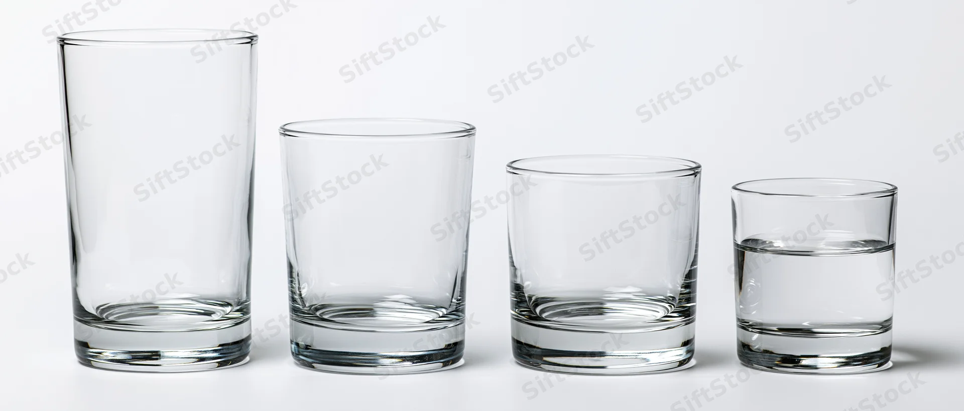 Four empty drinking glasses lined up in a row on a white background
