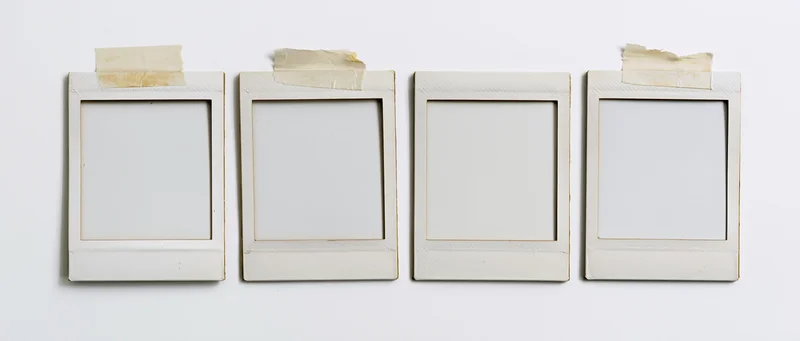 Four empty instant photo frames arranged in a row on a white surface