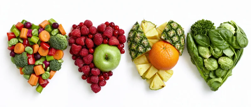 Four heart-shaped arrangements of fruits and vegetables on white background