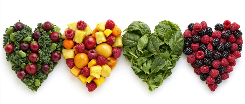 Four heart-shaped arrangements of fruits and vegetables on a white background
