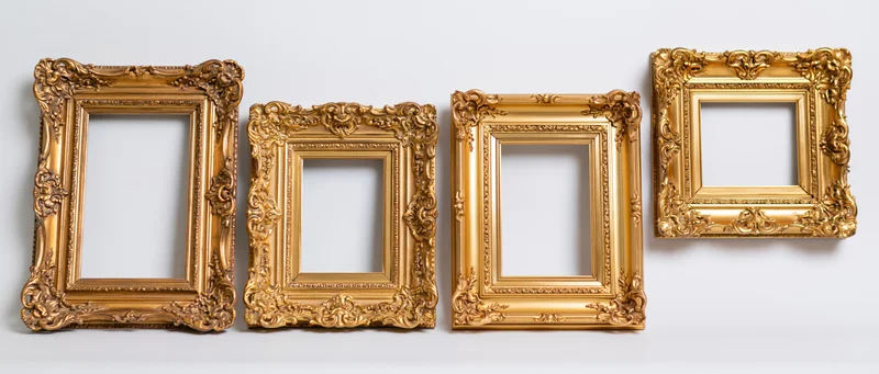 Four ornate gold picture frames arranged in a row against a white wall