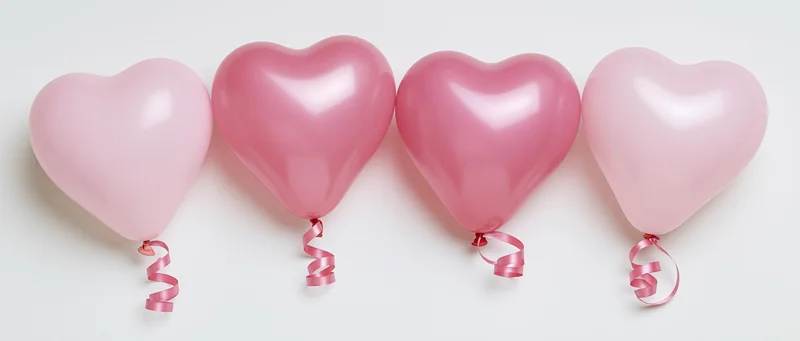 Four pink heart-shaped balloons arranged in a row on a white background
