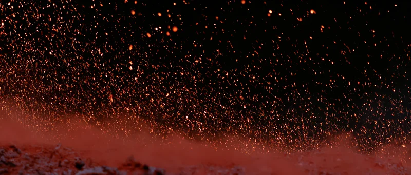 Glowing sparks rising upward against a dark background