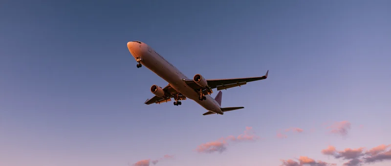 Commercial passenger jet in landing approach against twilight sky with pink clouds