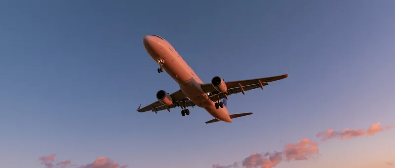 Commercial airplane in landing approach against twilight sky with pink clouds