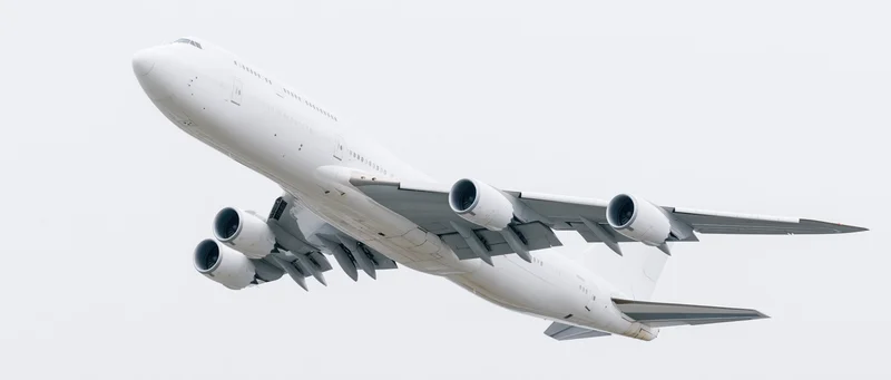 White commercial jet aircraft in flight against overcast sky
