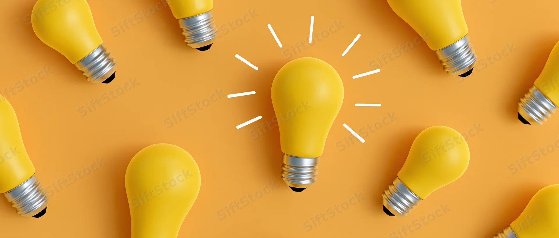 Yellow lightbulbs scattered in flat lay on orange surface with one glowing in center