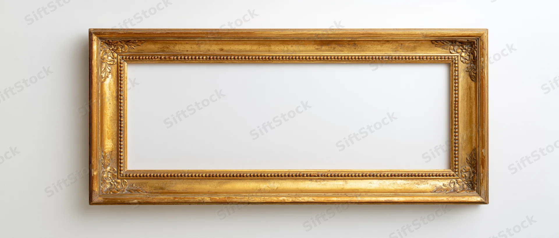 Ornate antique gold picture frame hanging on white wall with empty center for display