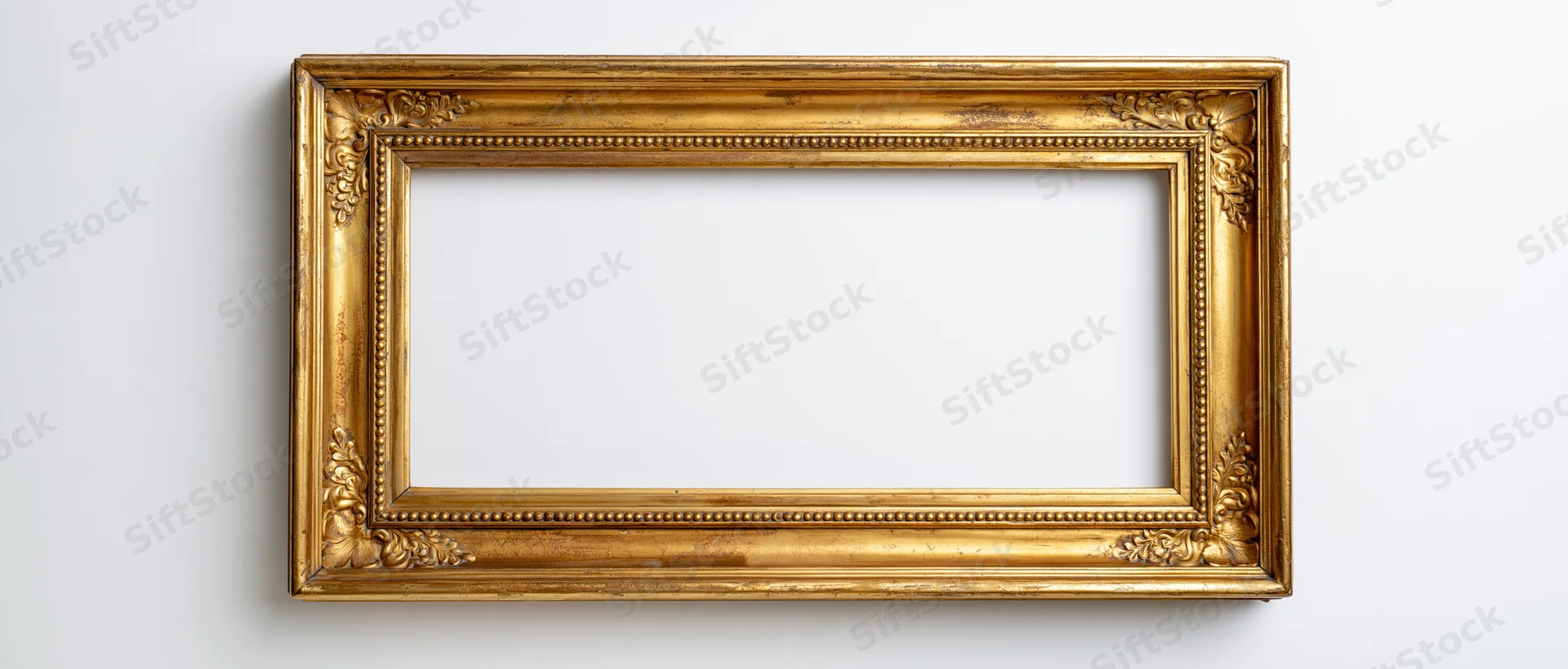 Ornate antique gold picture frame hanging on white wall with empty center for display