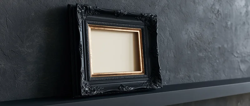 Ornate black baroque frame with gold trim resting on dark shelf against textured wall