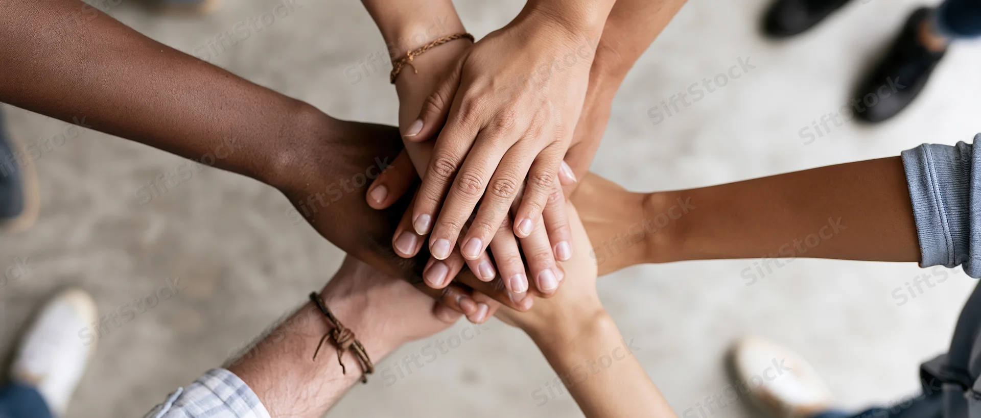 Six diverse hands stacked together in a circle from above