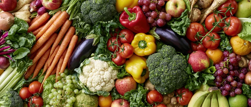 Overhead flat lay of a dense arrangement of fresh vegetables and fruits on a flat surface