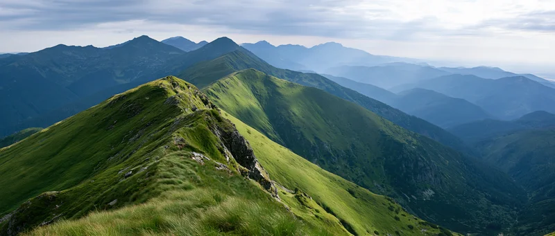 Panoramic view of layered green mountain ridges receding into the distance under an overcast sky