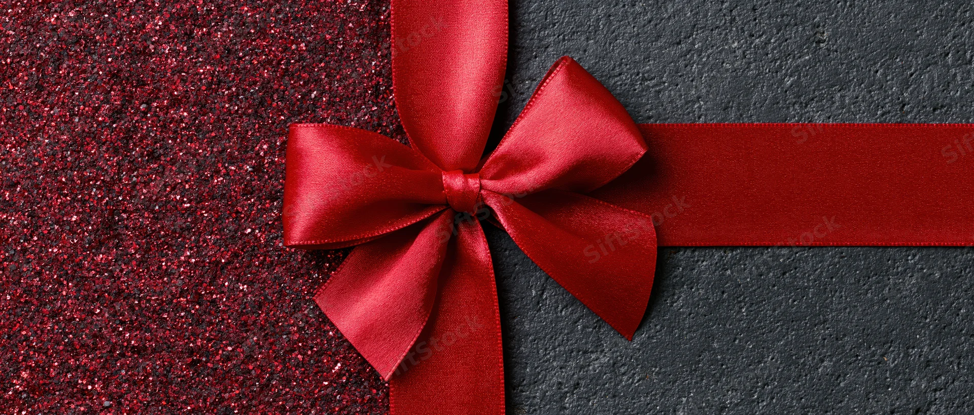 Red satin ribbon tied in a bow across a dark textured banner with glittery red side panel