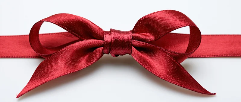 Red satin ribbon tied in a neat bow centered on a white background