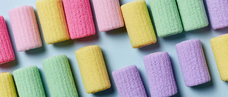 Rows of colorful velcro hair rollers arranged in flat lay on light blue surface