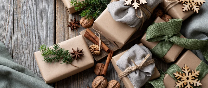 Christmas gifts wrapped in kraft paper with natural decorations on wooden surface