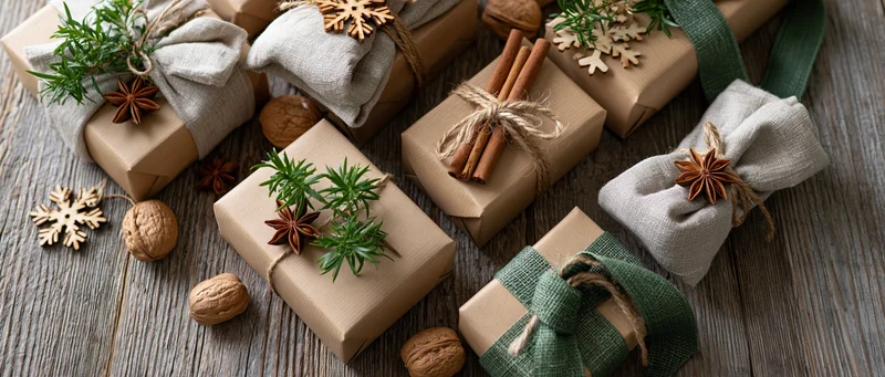 Christmas gifts wrapped in kraft paper with natural decorations on wooden surface