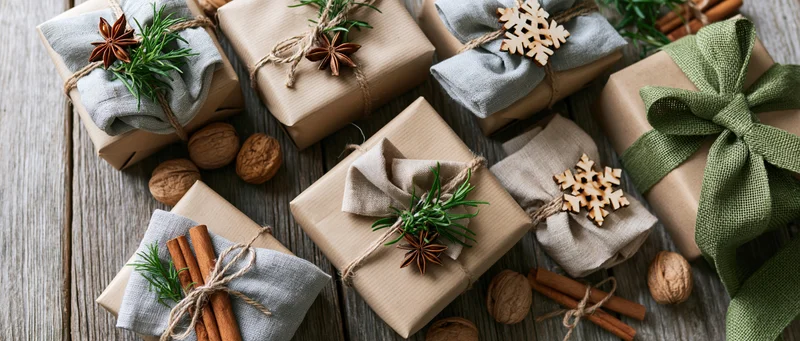 Christmas gifts wrapped in kraft paper with natural decorations on wooden surface