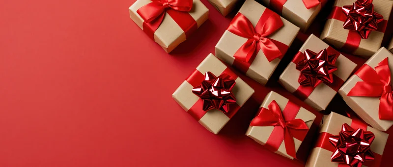 Kraft paper gift boxes with red satin ribbons arranged on red background