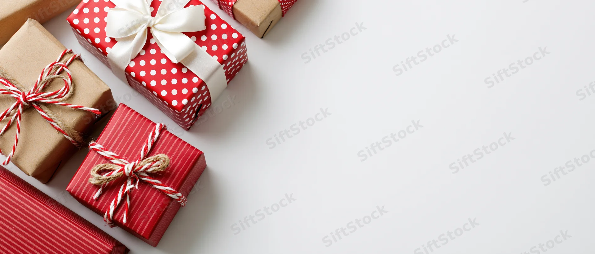 Wrapped christmas gift boxes arranged along the left side on white surface