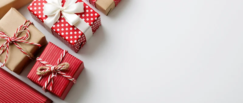 Wrapped christmas gift boxes arranged along the left side on white surface