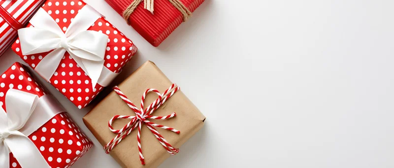 Christmas gift boxes wrapped in red and white paper with bows arranged along the left on white background