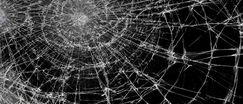 Shattered glass pane with multiple impact points radiating cracks across the surface