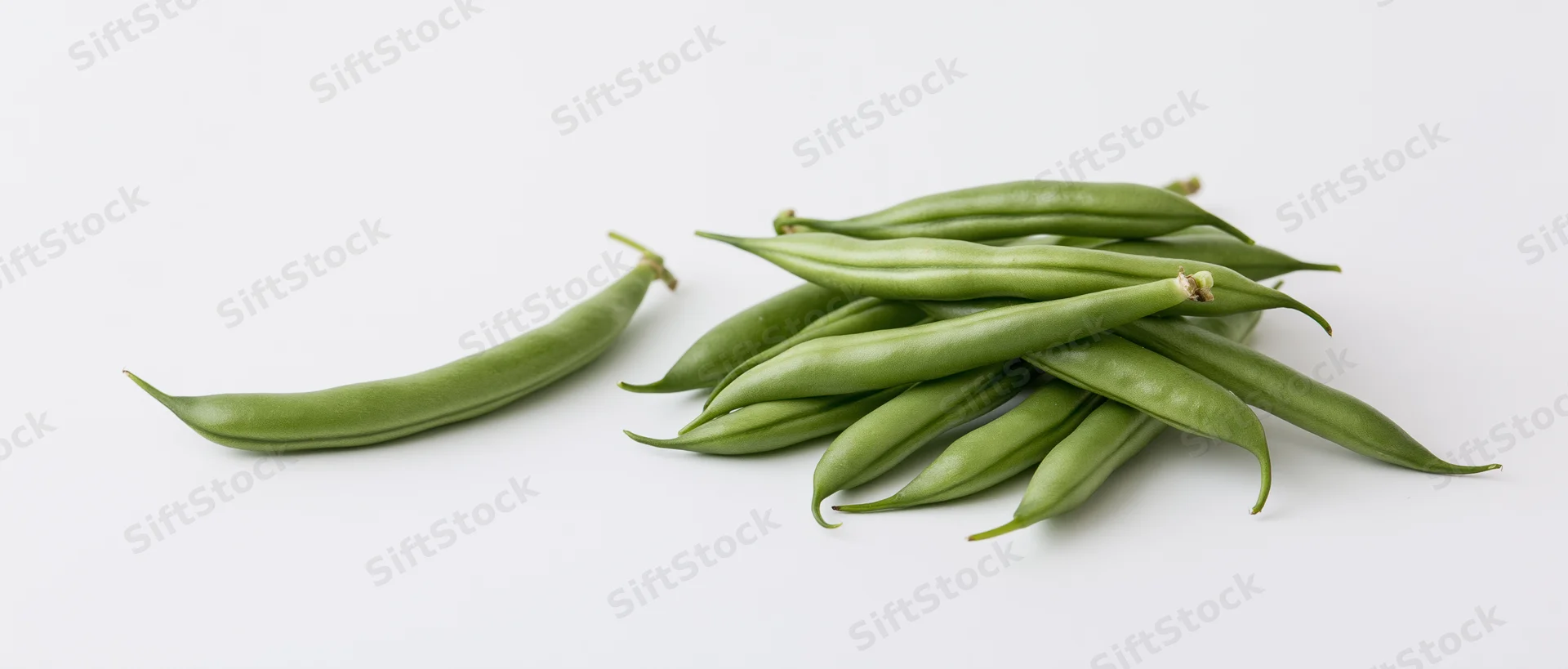 Fresh green beans arranged in small pile with one separate pod on white background