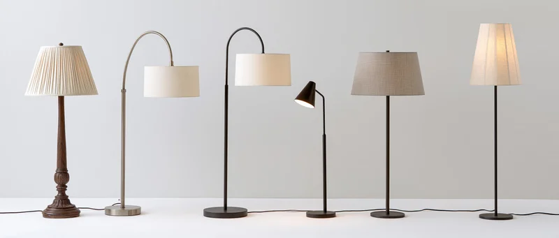 Six floor lamps arranged in a row on a white surface against a plain white background