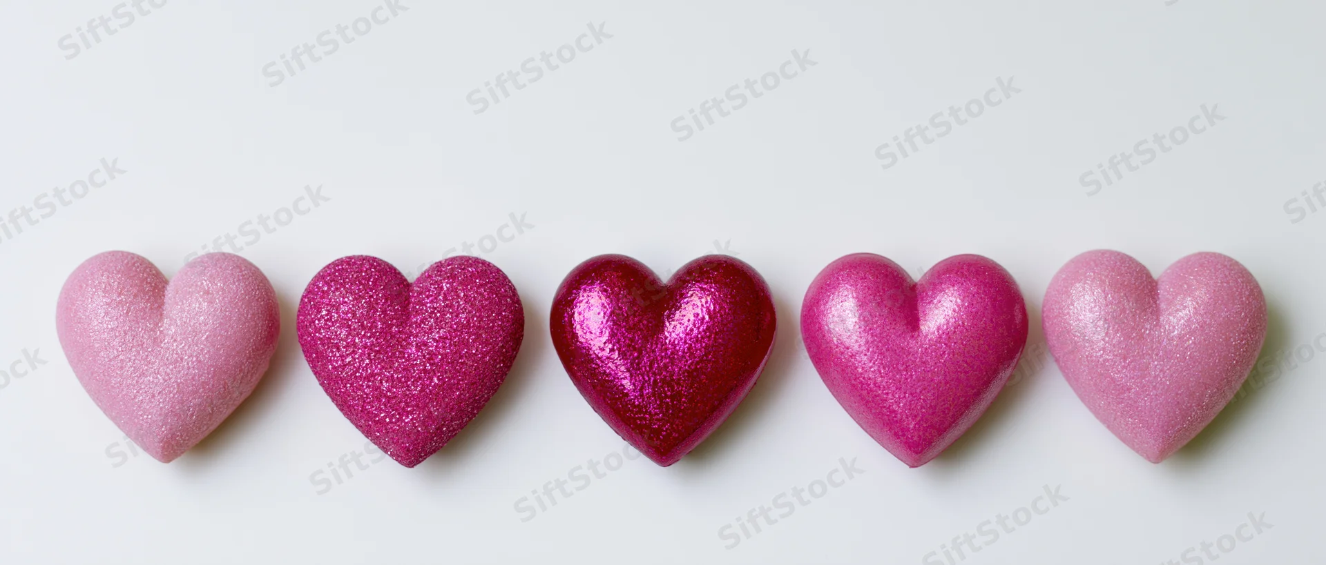 Five pink glitter hearts arranged in a horizontal row on a white background