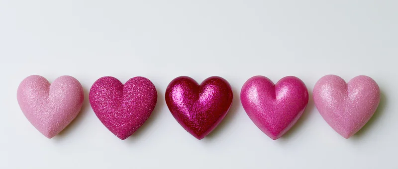 Five pink glitter hearts arranged in a horizontal row on a white background