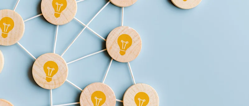 Wooden tokens with yellow lightbulb icons connected by sticks on a blue surface