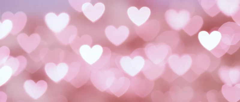 Soft abstract background of blurred heart-shaped bokeh lights in pink and white