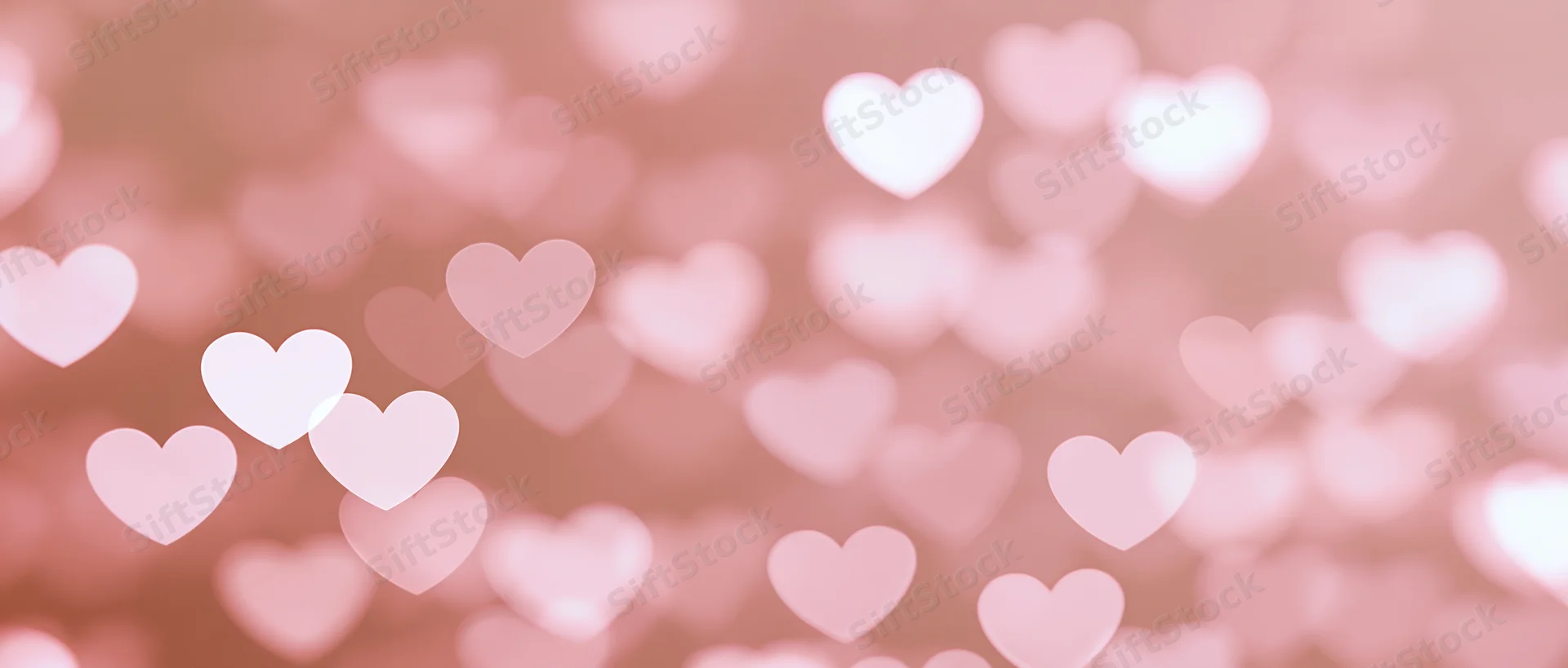 Soft pink bokeh background with heart-shaped lights scattered across the frame