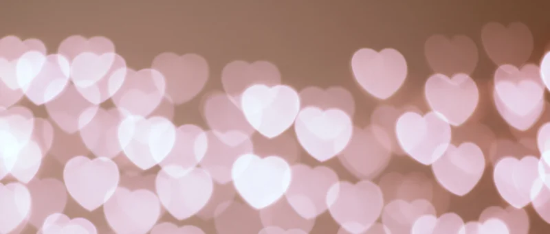Soft pink heart-shaped bokeh lights forming a blurred romantic background