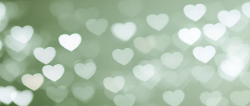 Soft bokeh background with out-of-focus white heart shapes on a muted green tone