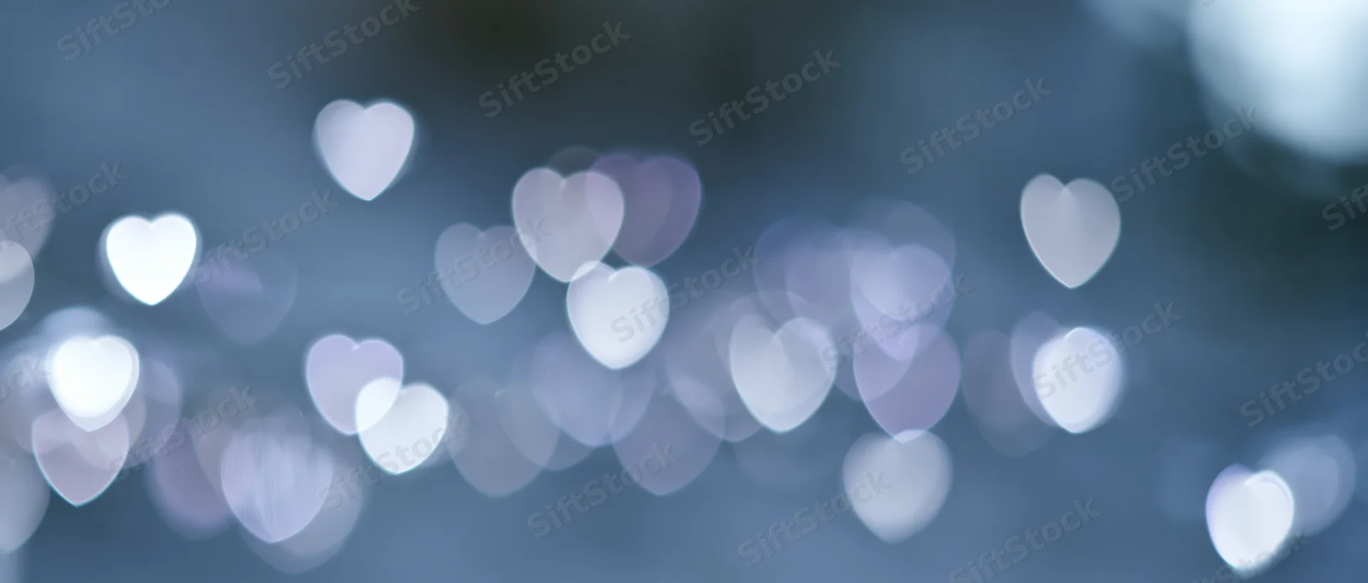 Soft out-of-focus bokeh background with scattered heart-shaped lights in cool tones