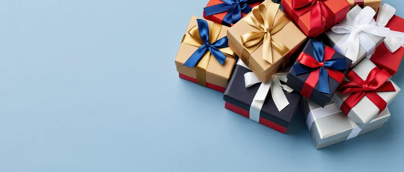 Stack of wrapped gift boxes piled together on light blue surface with copyspace